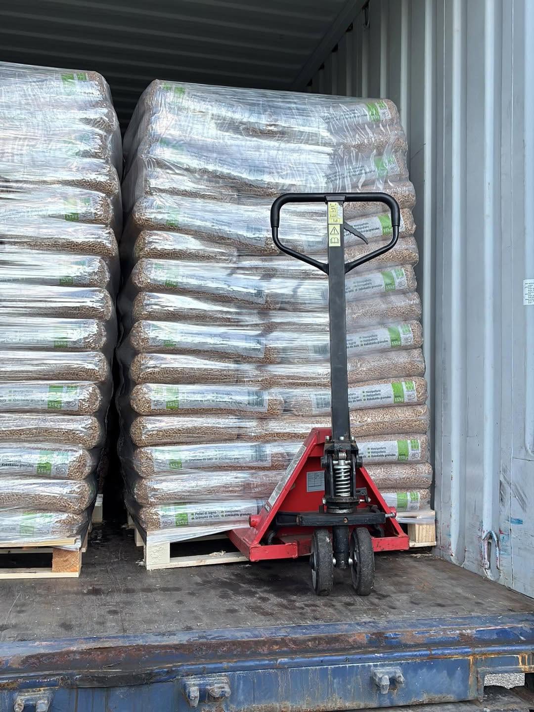 Palletised pellet bags and a pallet jack inside a shipping container