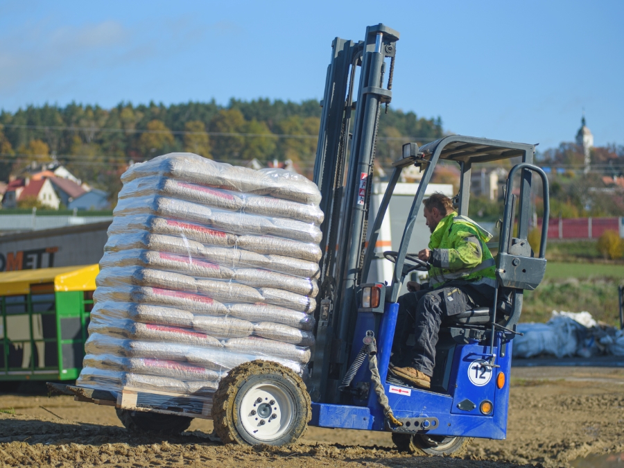 A forklift handling a pallet of bagged wood pellets